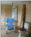 Shower room, showing tower shower, chair/wet floor